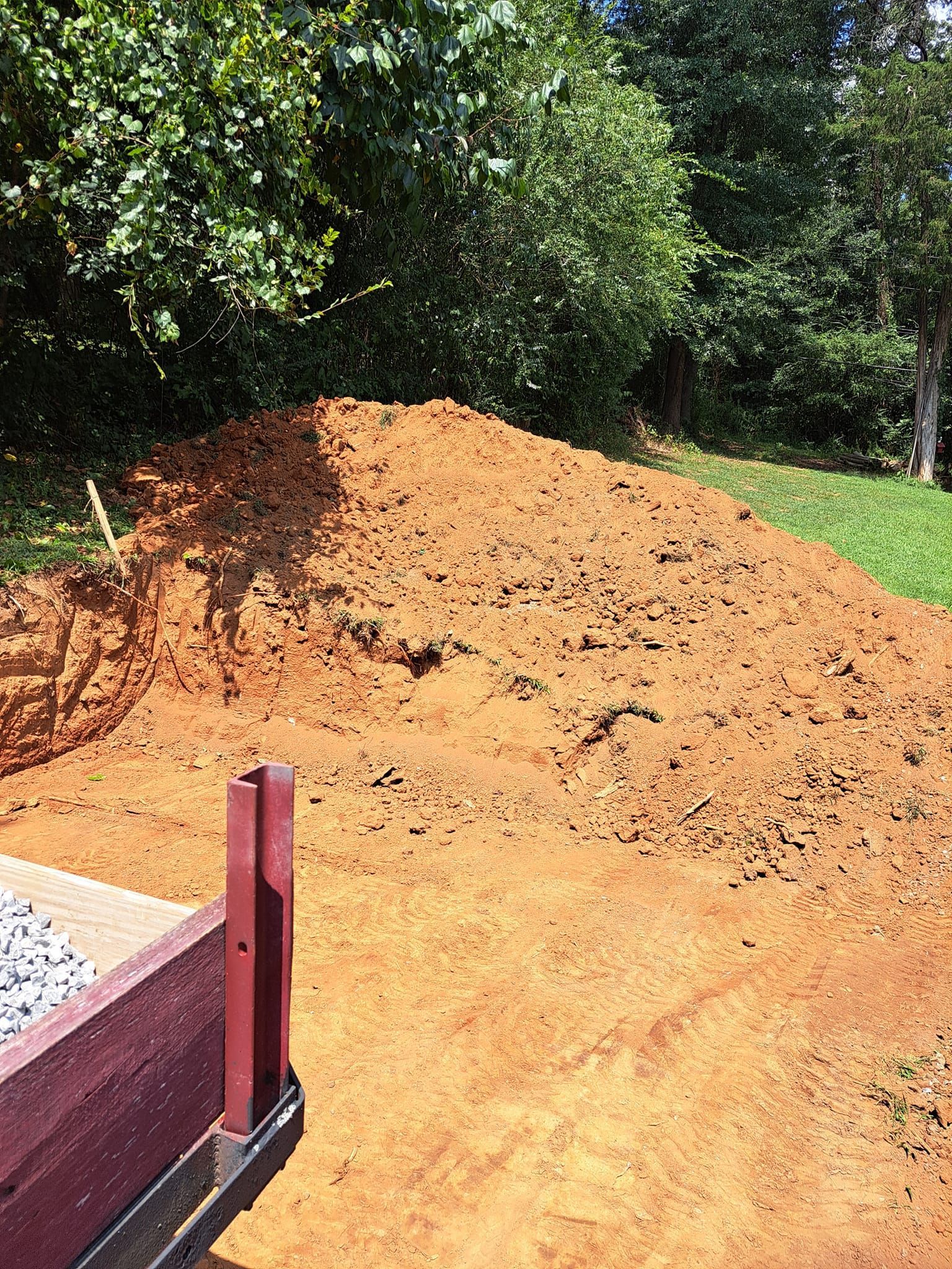 A pile of dirt is sitting on top of a dirt road next to a truck.