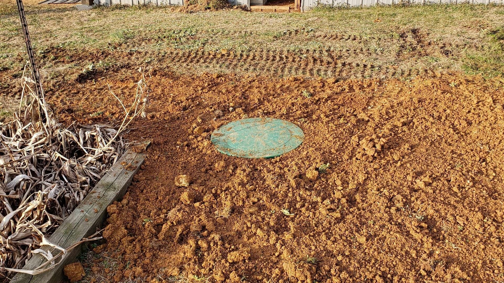 A green lid is sitting in the middle of a pile of dirt.