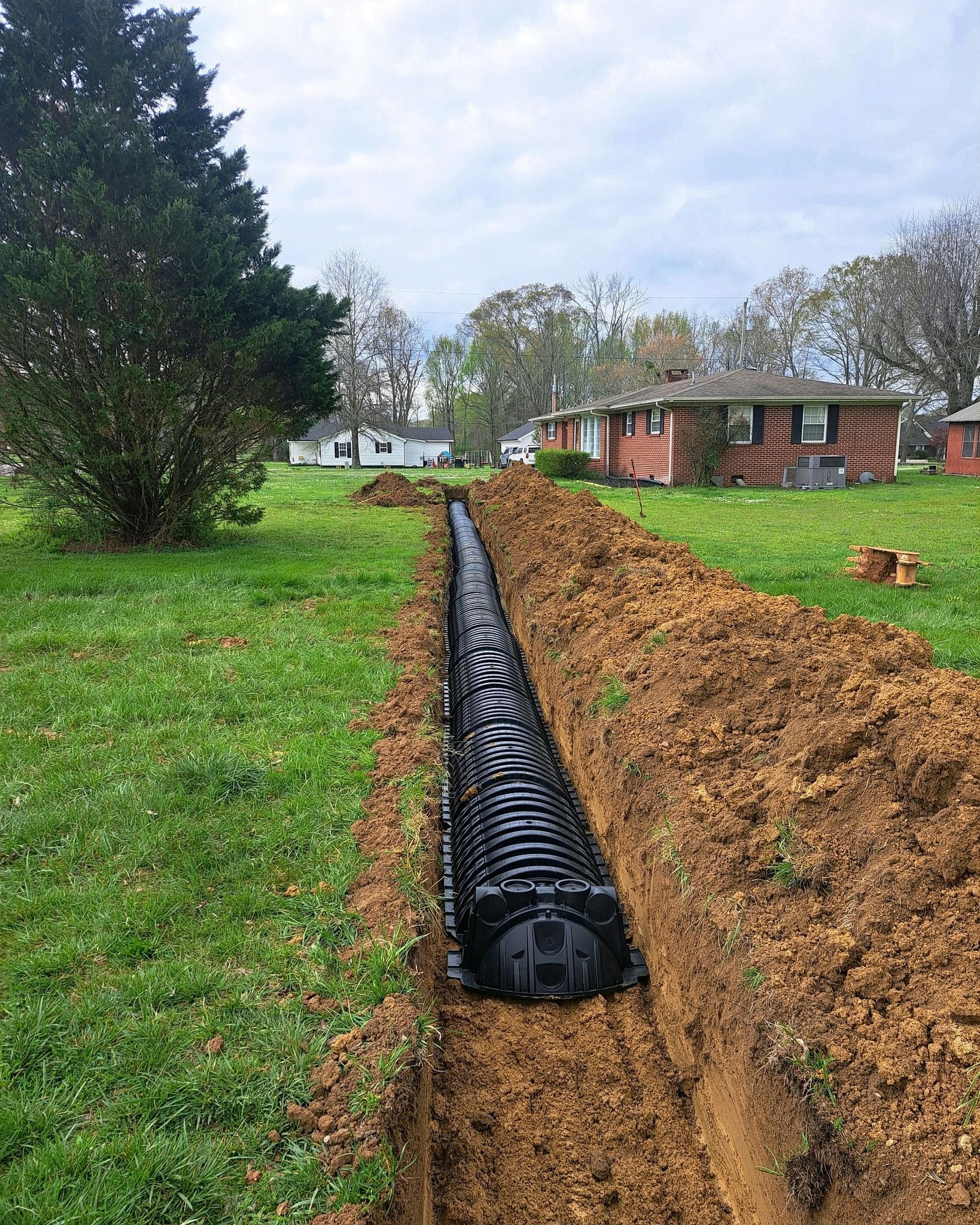 A drainage system is being installed in a yard next to a house.