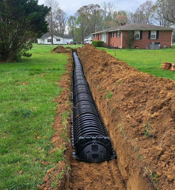 A drainage system is being installed in a yard next to a house.