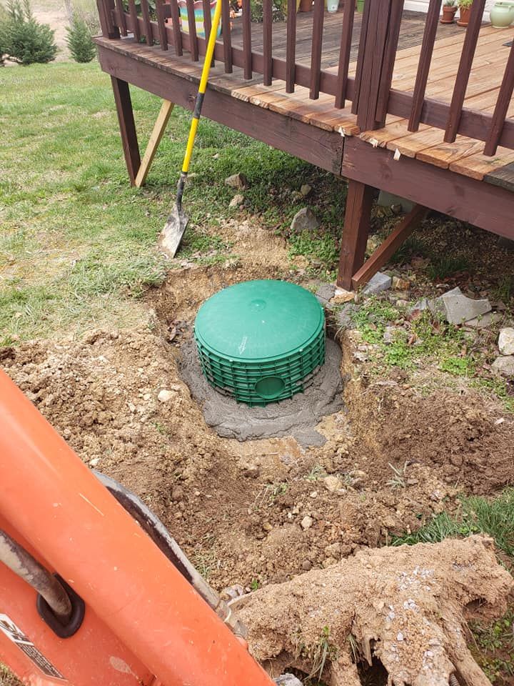 A green septic tank is being installed under a deck.