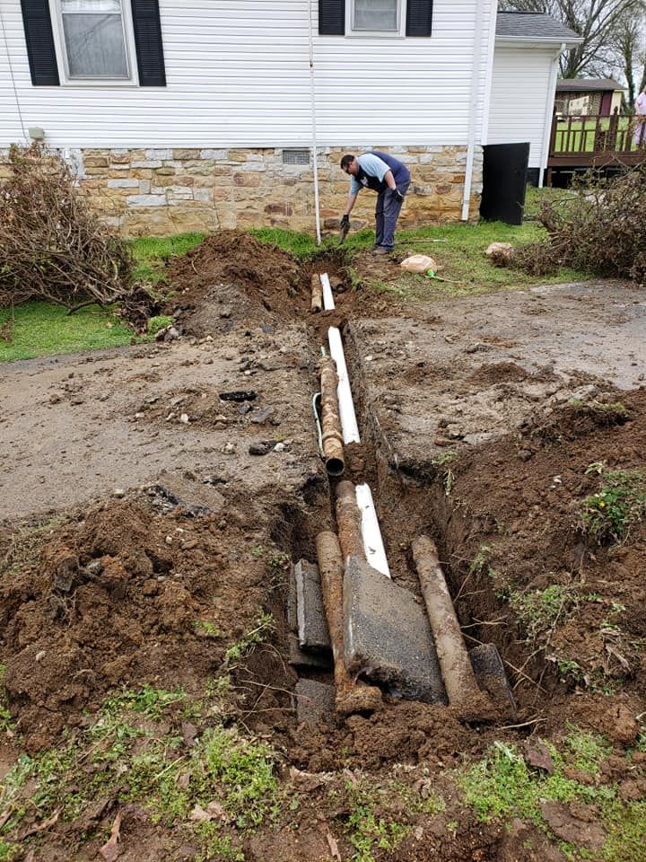 A man is digging a hole in the dirt in front of a house.