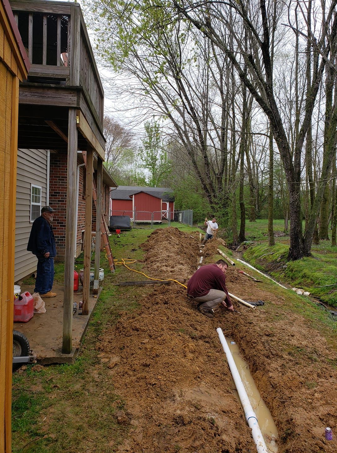 A man is digging a hole in the dirt in front of a house.