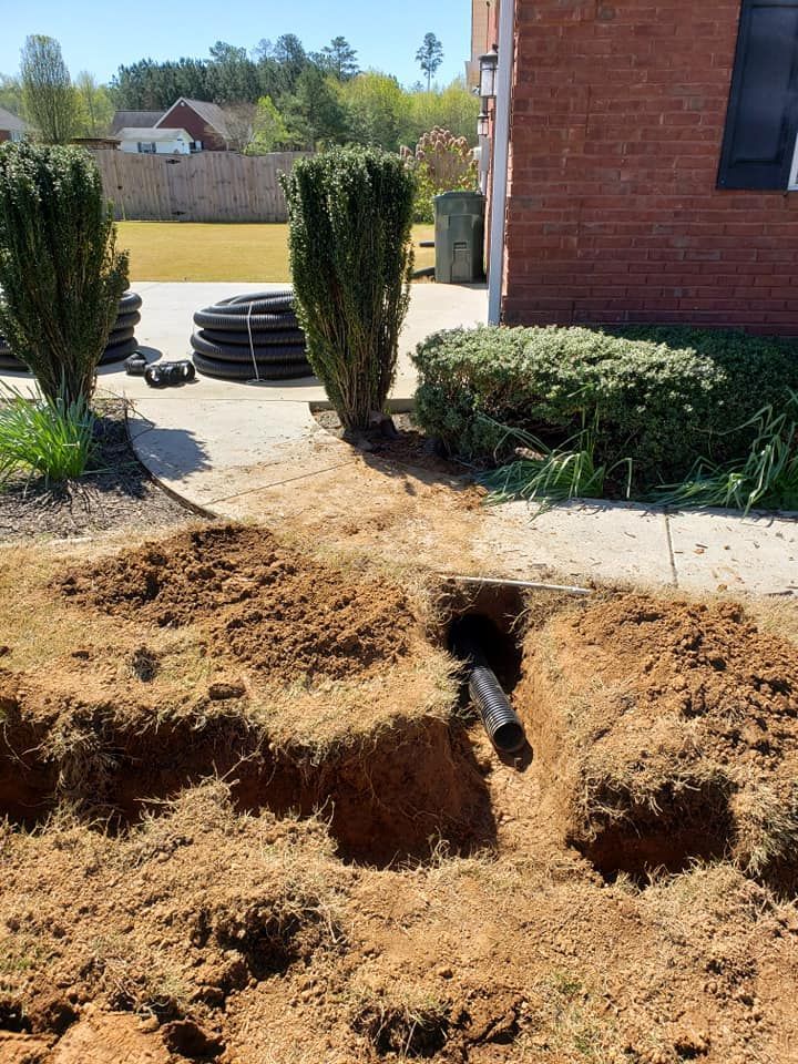 A pipe is being installed in the dirt in front of a house.