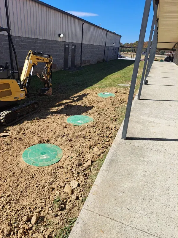 A yellow excavator is sitting in the dirt in front of a building.