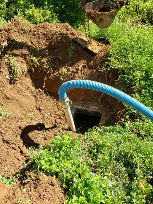 A blue hose is connected to a hole in the ground.