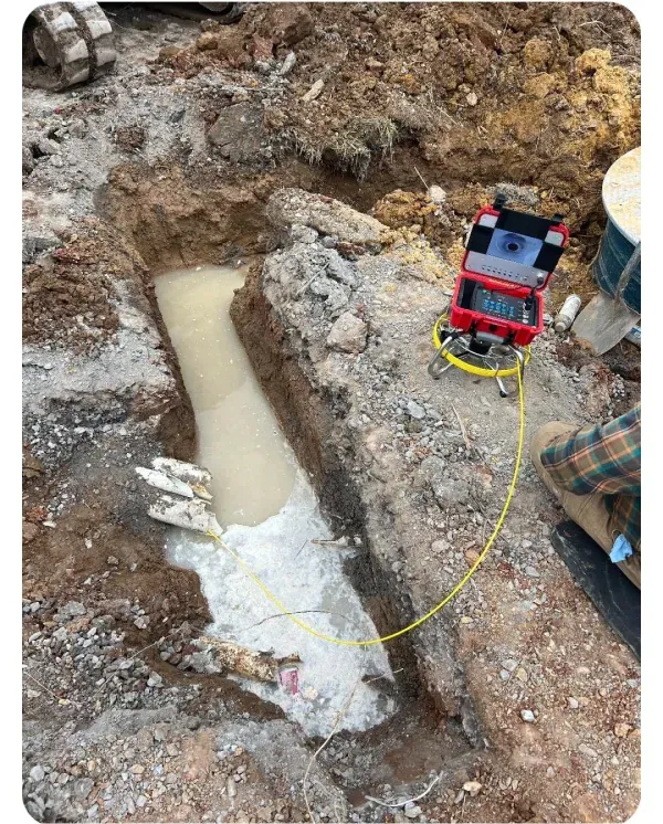 A camera is sitting in the dirt next to a hole in the ground.