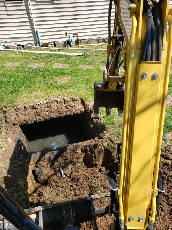 A yellow excavator is digging a hole in the ground