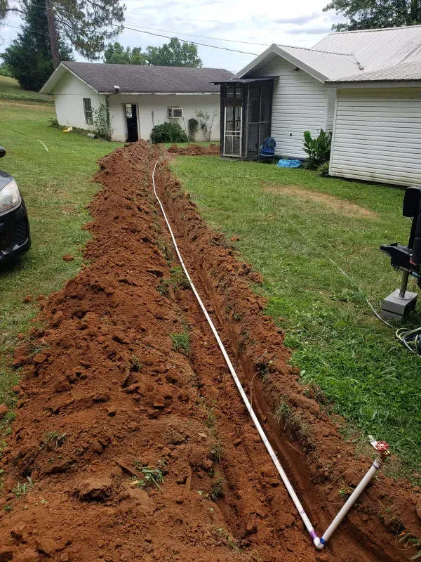 A hose is laying in the dirt in front of a house.