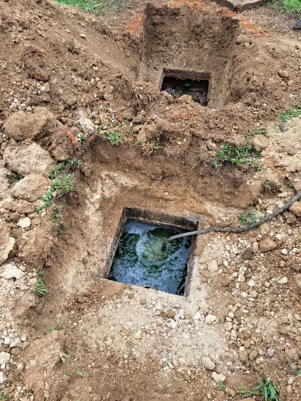Two septic tanks are being installed in the dirt.