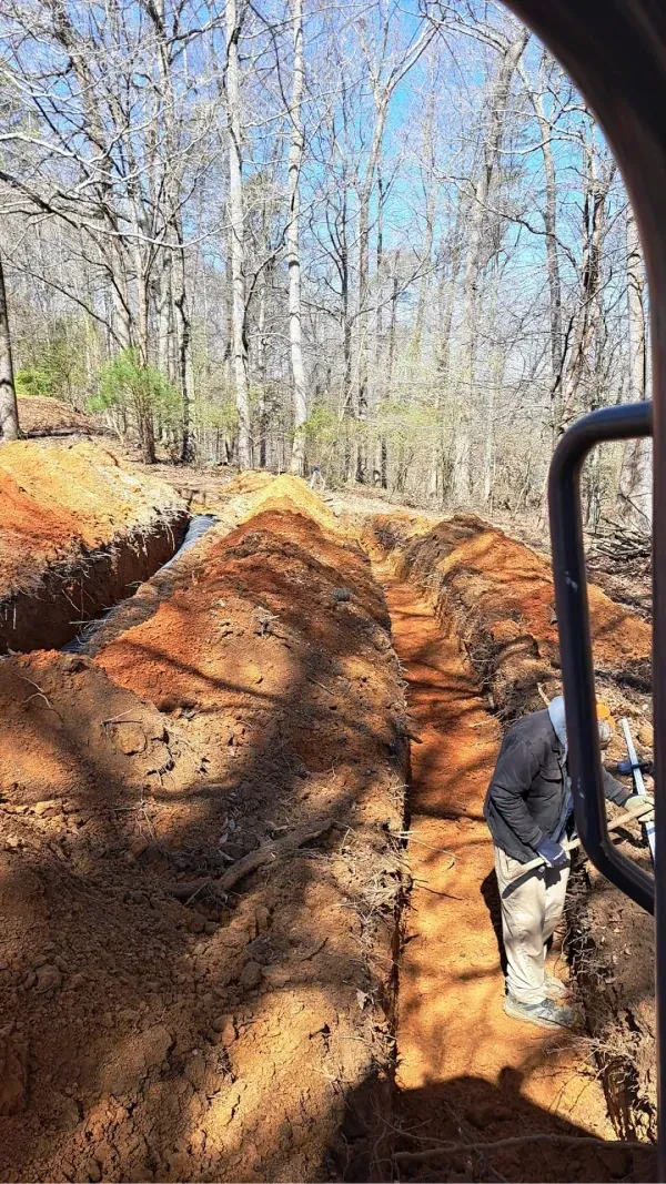 A man is standing in a trench in the woods.