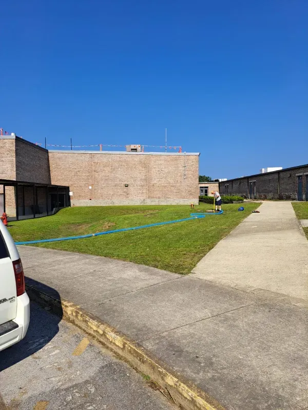 A white van is parked in front of a large brick building.