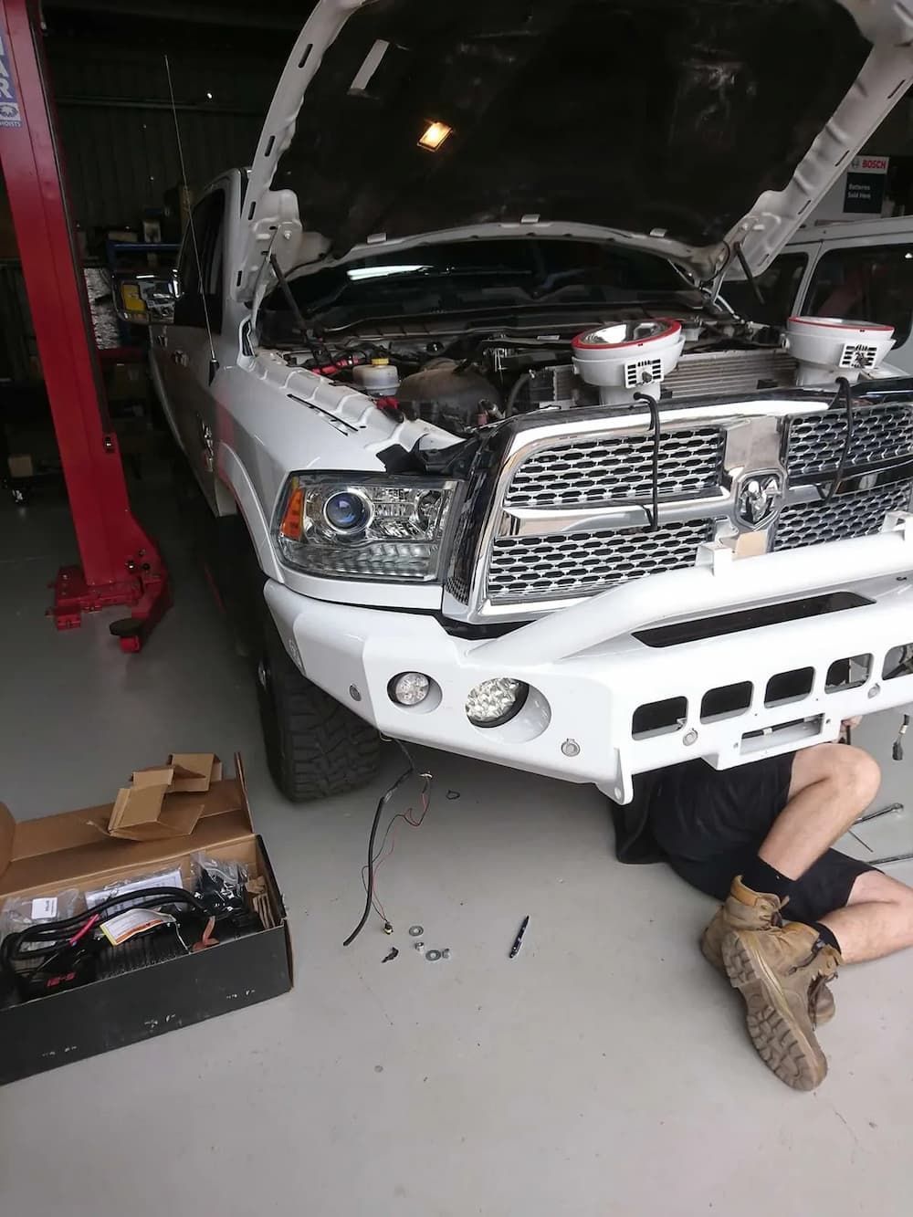 A Man Is Working Under The Hood Of A White Truck — KC Auto Electrics In Ciccone, NT