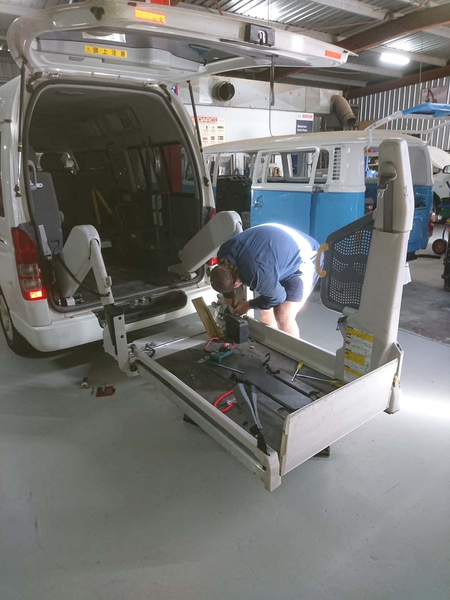 A Man Is Working On A Lift In The Back Of A Van — KC Auto Electrics In Ciccone, NT