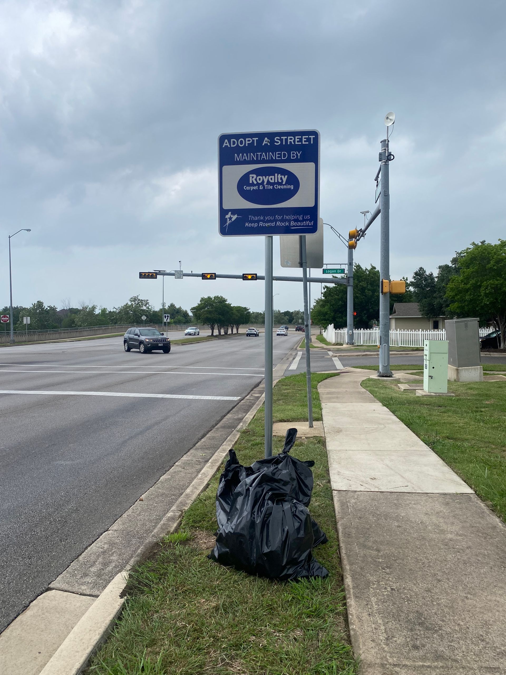 A trash bag is laying on the sidewalk next to a street sign