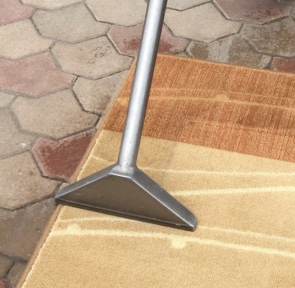 A vacuum cleaner is being used to clean a rug