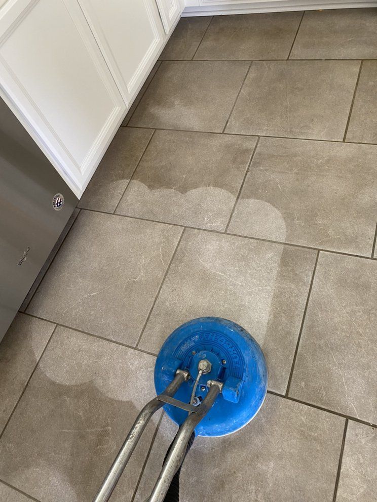 A person is cleaning a tiled floor with a machine.