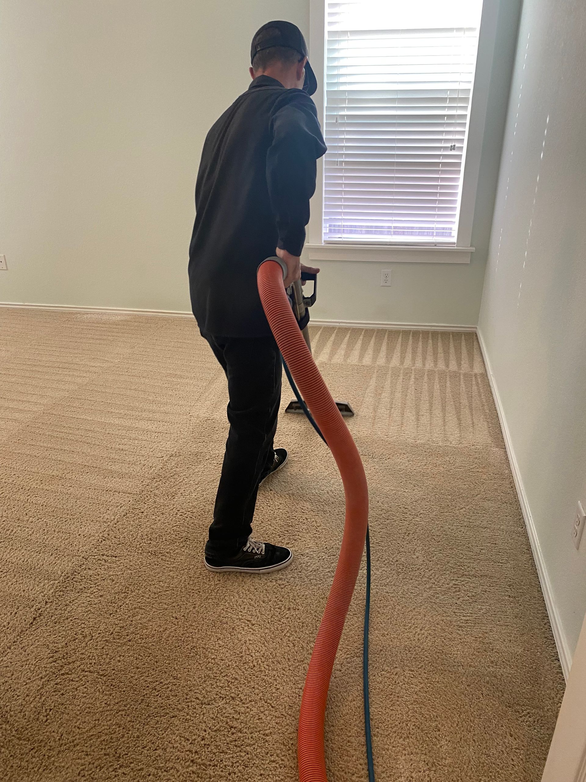 A person is using a vacuum cleaner to clean a carpet.