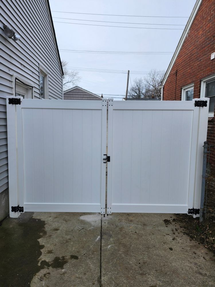 White double gate between two buildings; overcast sky.
