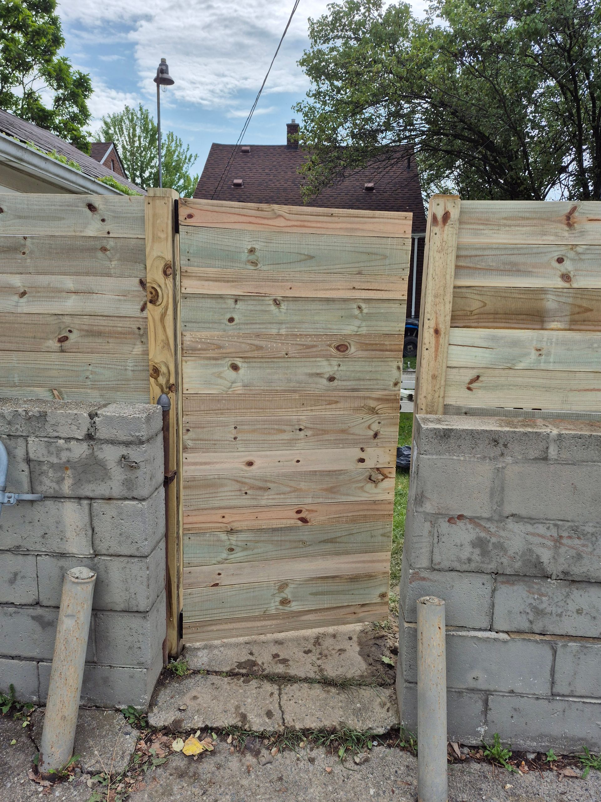 Wooden gate and fence built between cinder block walls.