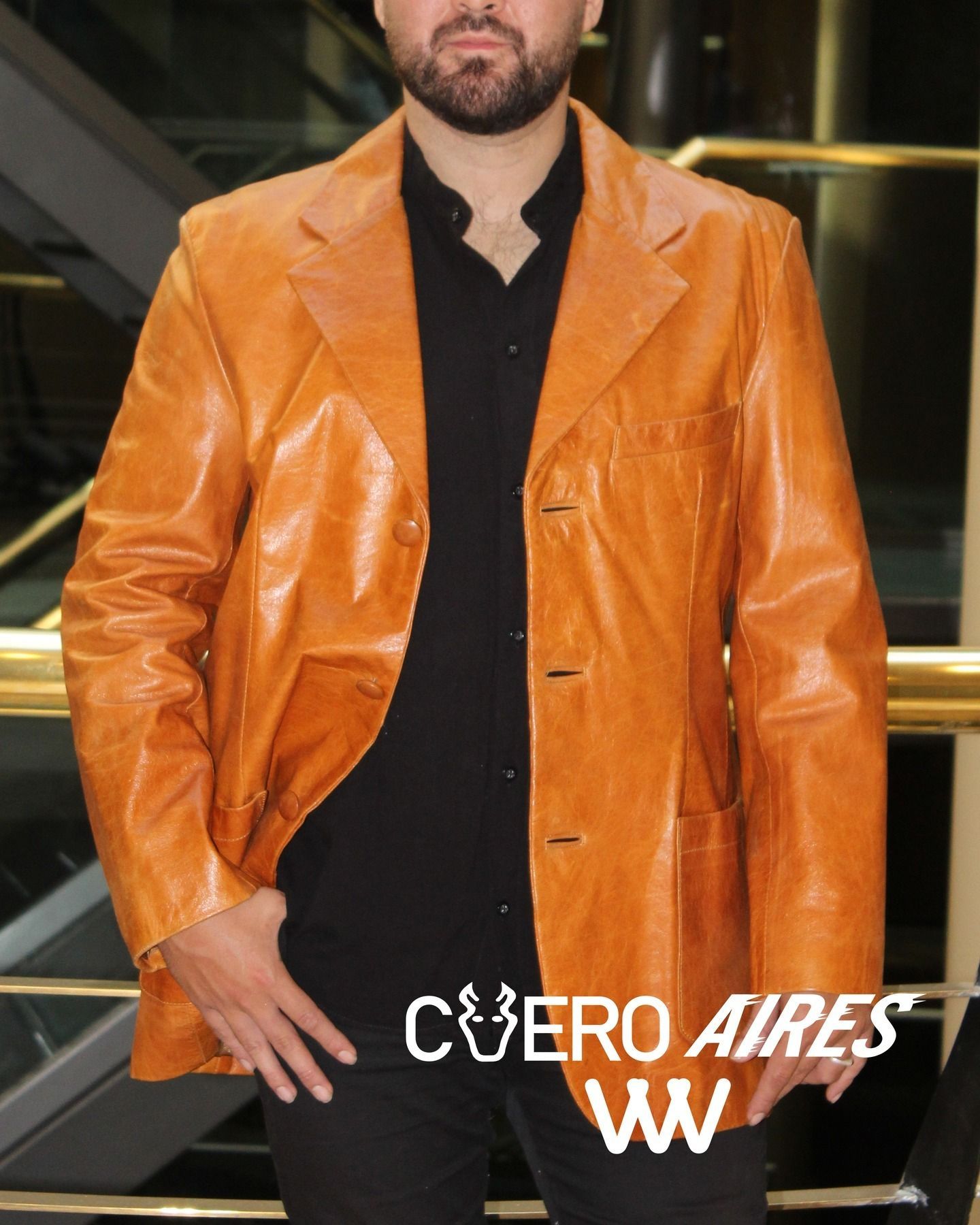 Hombre con chaqueta de cuero color canela y camisa negra. Marca de agua 