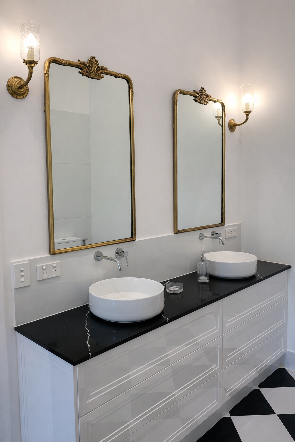 Modern bathroom with white vanity, black countertop, gold mirrors, and white sinks — Paul Tagget Kitchens In Goonellabah, NSW