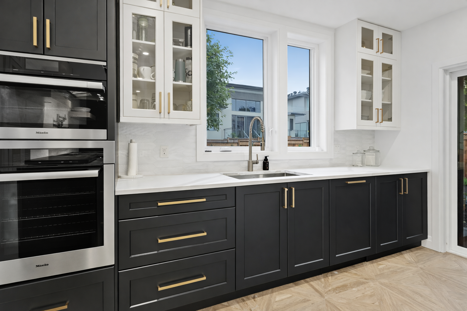 Modern kitchen with black cabinets, white countertops, and gold hardware. Stainless steel appliances — Paul Tagget Kitchens In Goonellabah, NSW