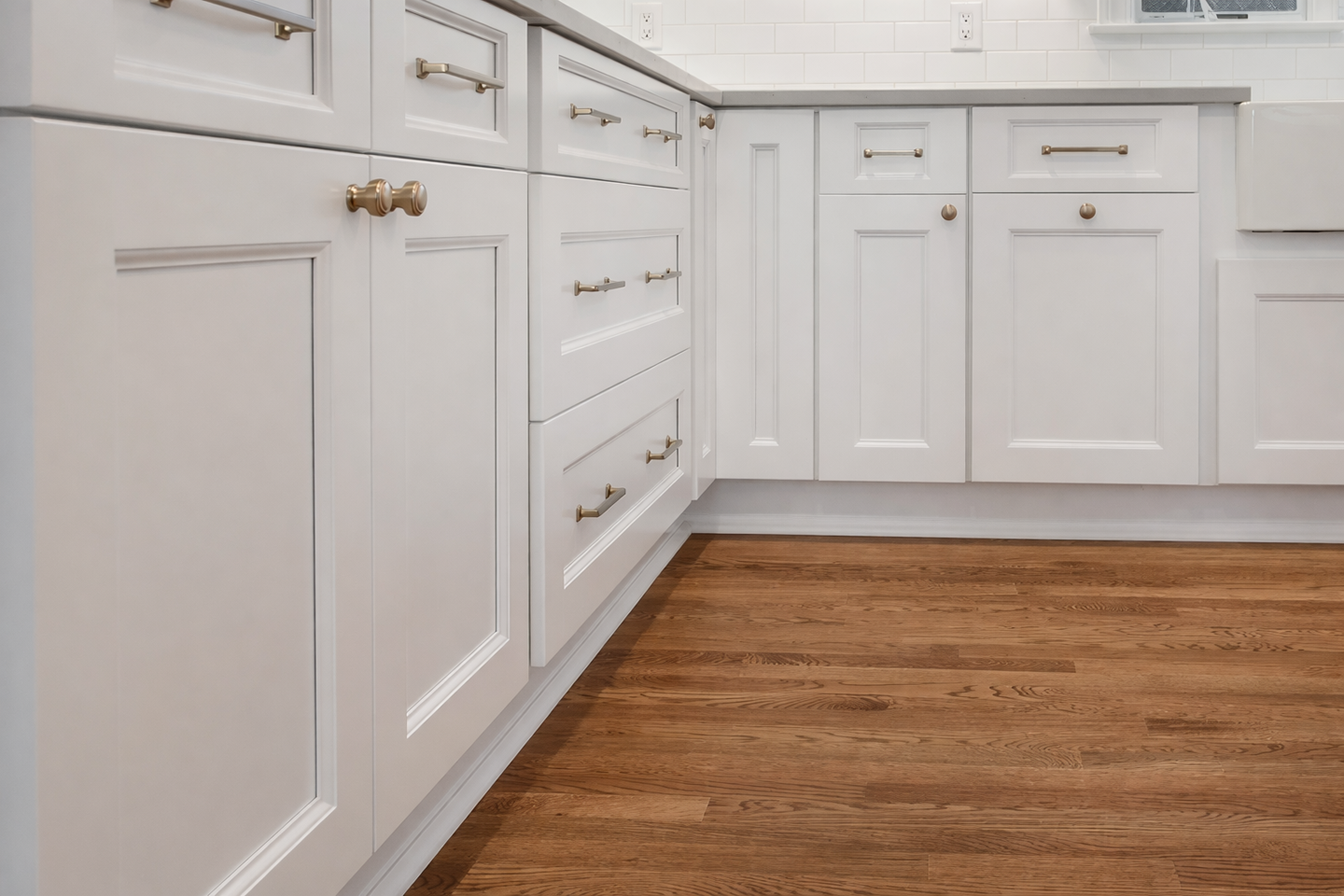 White Kitchen Cabinets And Drawers Along A Hardwood Floor In A Modern Kitchen
