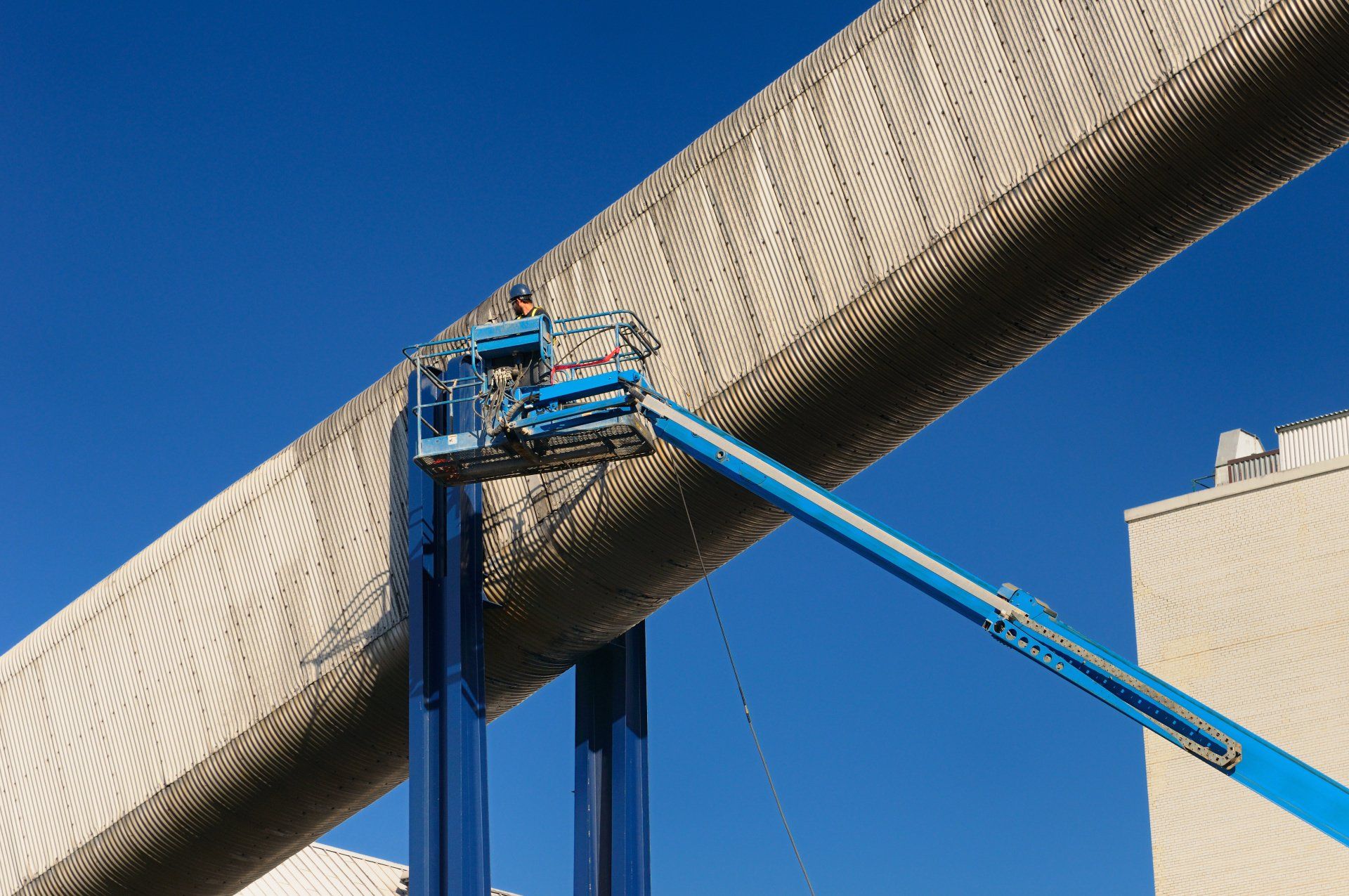 A man is working on a large pipe with a crane.