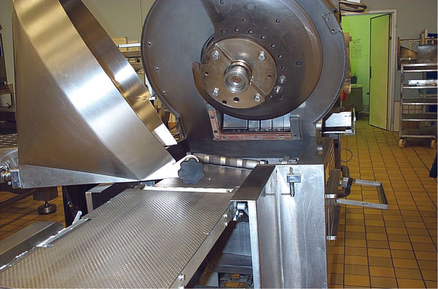 A large stainless steel machine is sitting on a conveyor belt in a kitchen