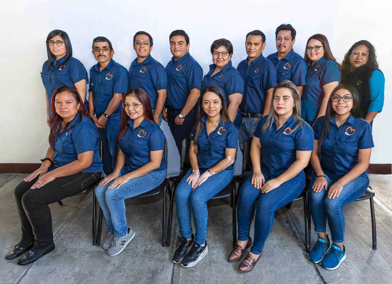 Grupo de personas con camisas azules, posando para una foto contra una pared blanca.