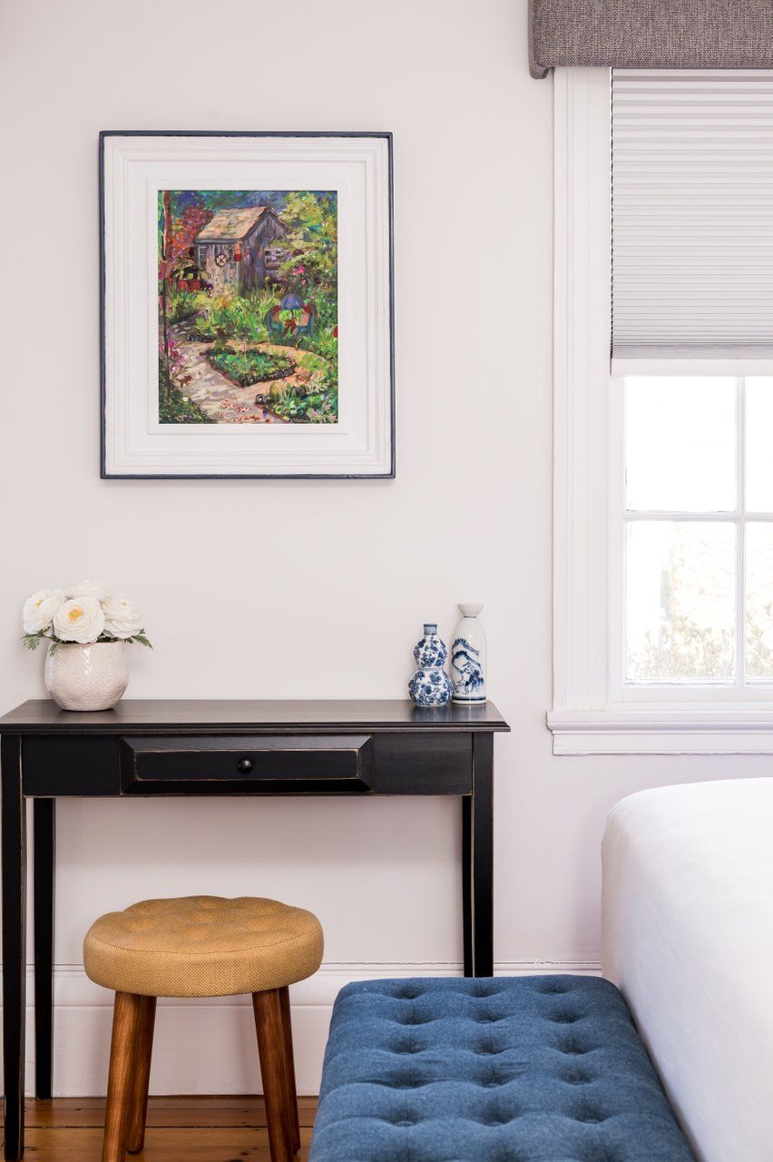 There is a painting on the wall above the desk in the bedroom.