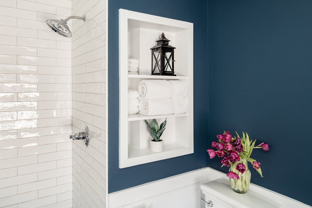 There is a vase of flowers on the toilet in the bathroom.