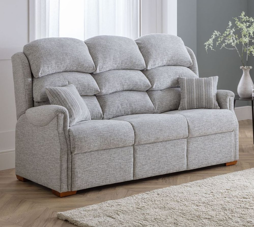 A grey couch is sitting in a living room next to a window.