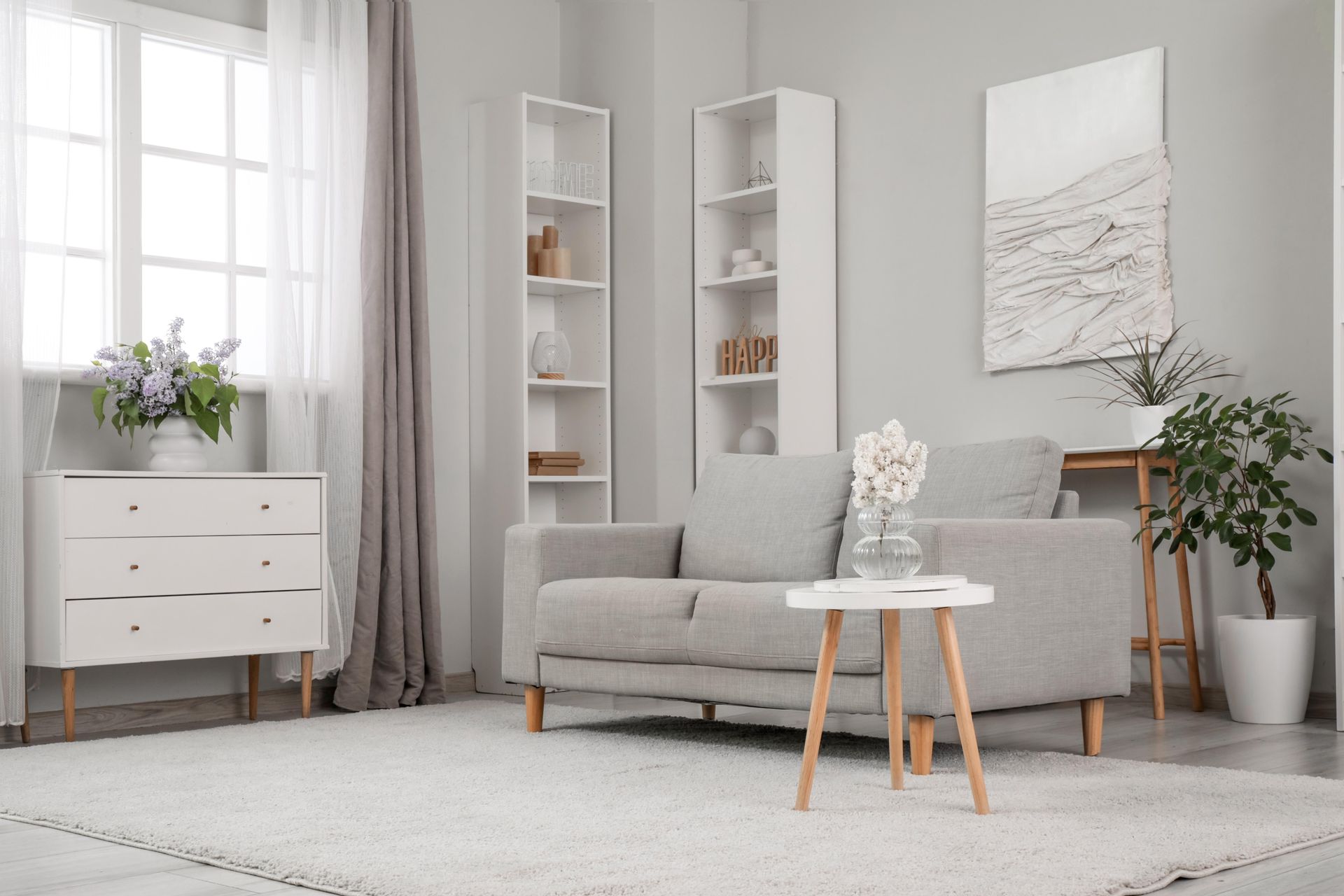 A living room with a couch , two tables , and a window.