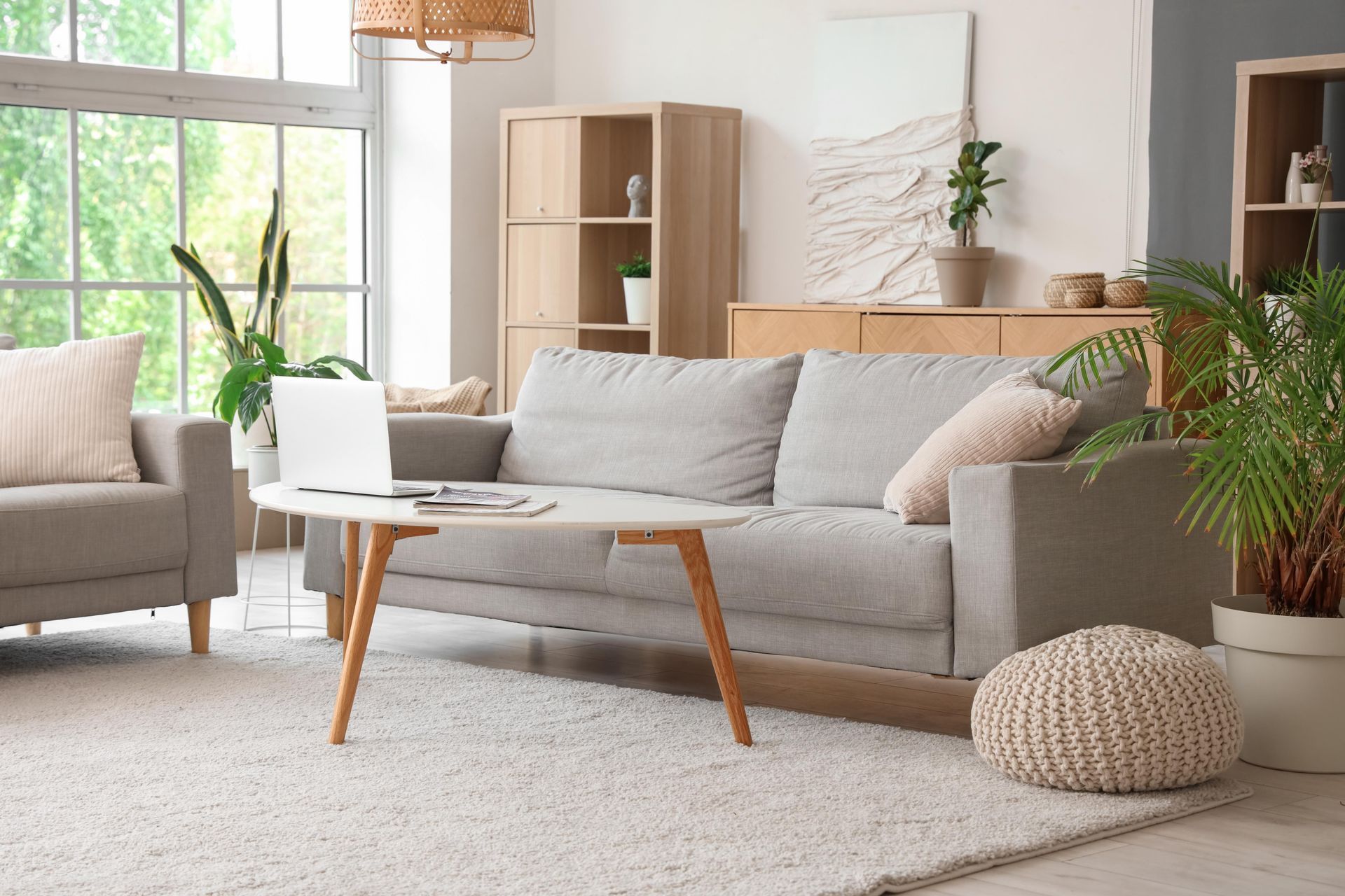 A living room with a couch , chair , coffee table and laptop.