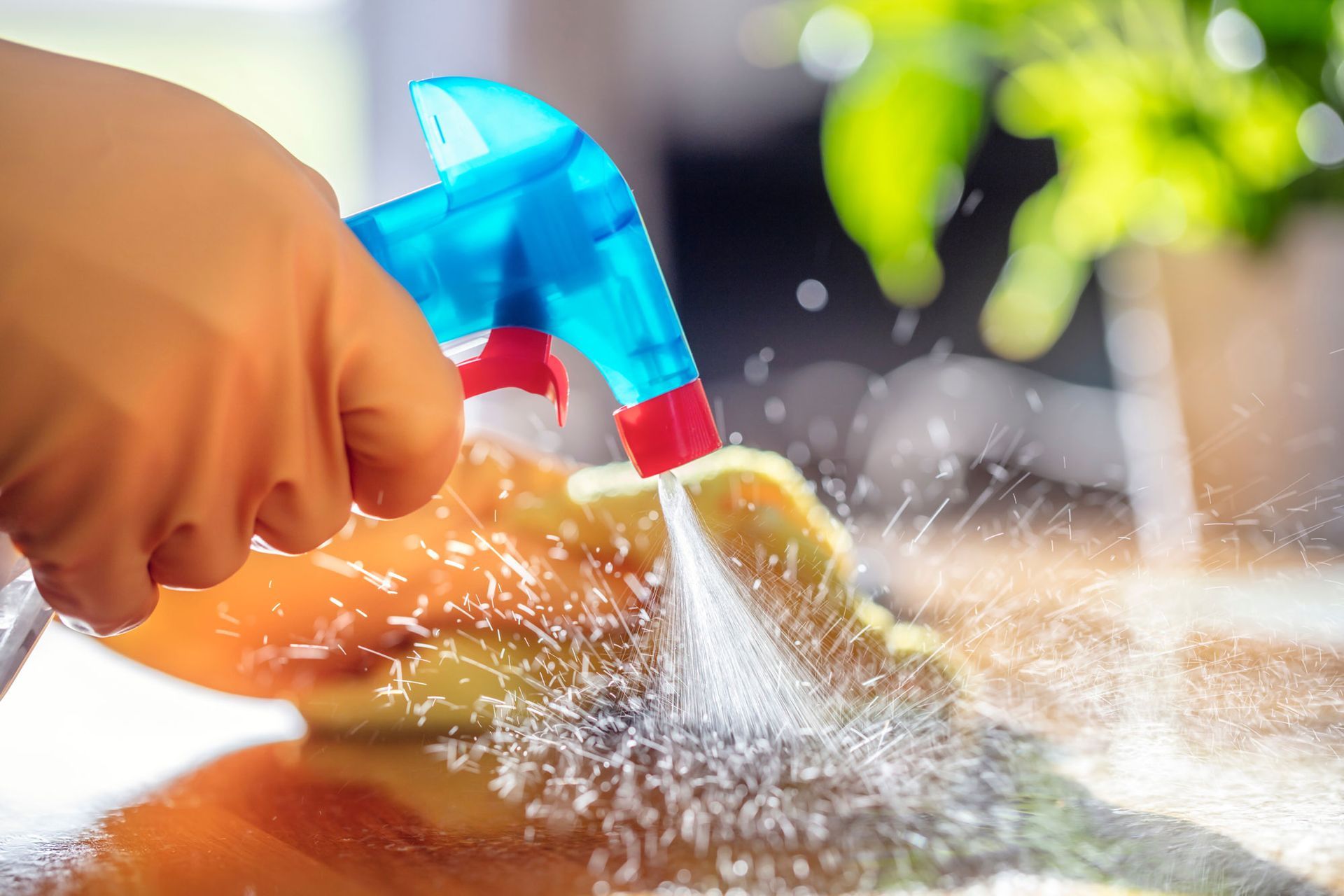 A person is spraying water on a cutting board with a spray bottle.