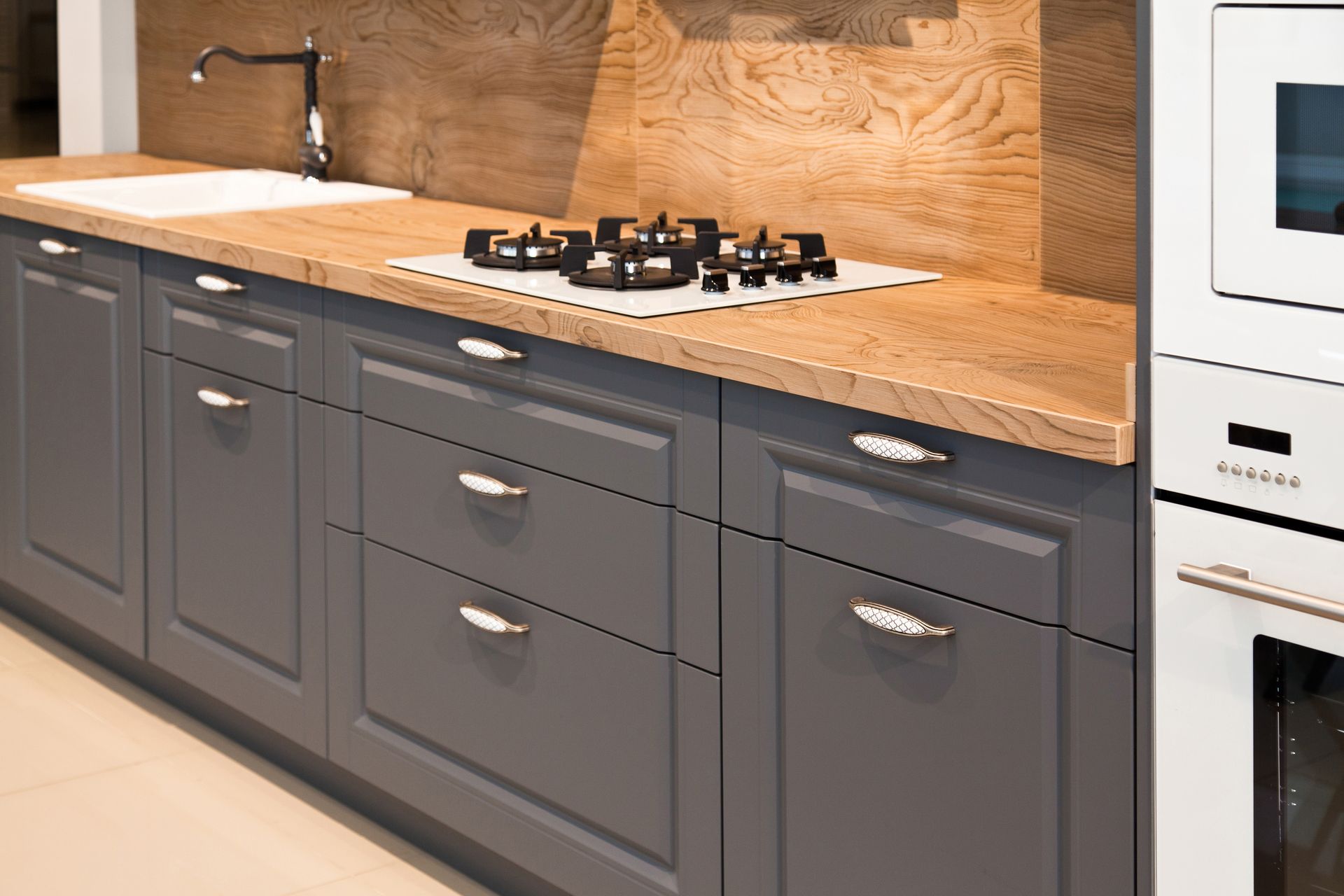 Gray kitchen cabinets with a wooden countertop and a gas stove.