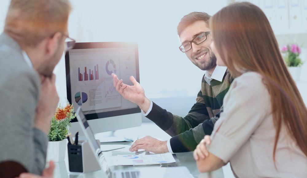 Three People at A Desk Looking at A Computer Screen — Freedom Wealth Solutions In Mornington, VIC