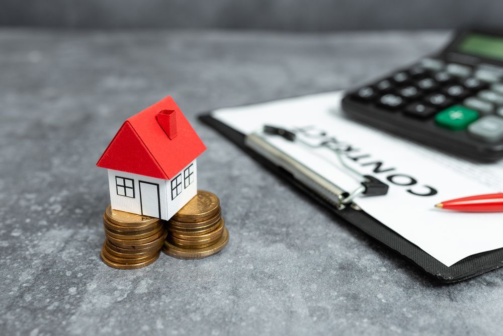 A Small Paper House on Coins Next to a Contract — Freedom Wealth Solutions In Frankston, VIC