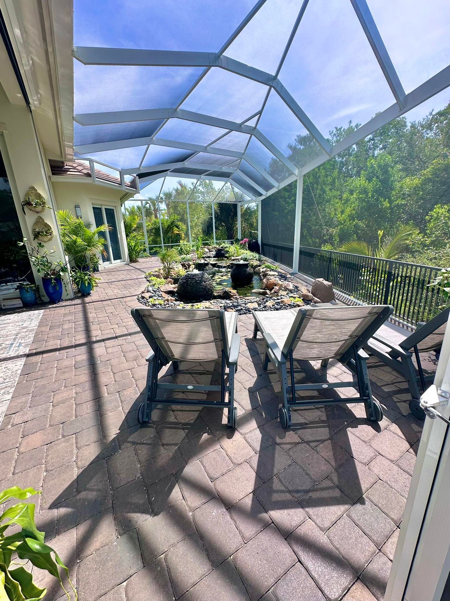 Woman in straw hat smiles, holding wine glass near a lake.
