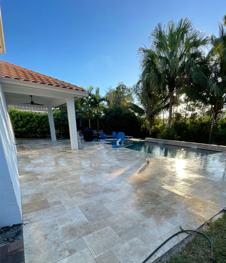 Woman in straw hat smiles, holding wine glass near a lake.