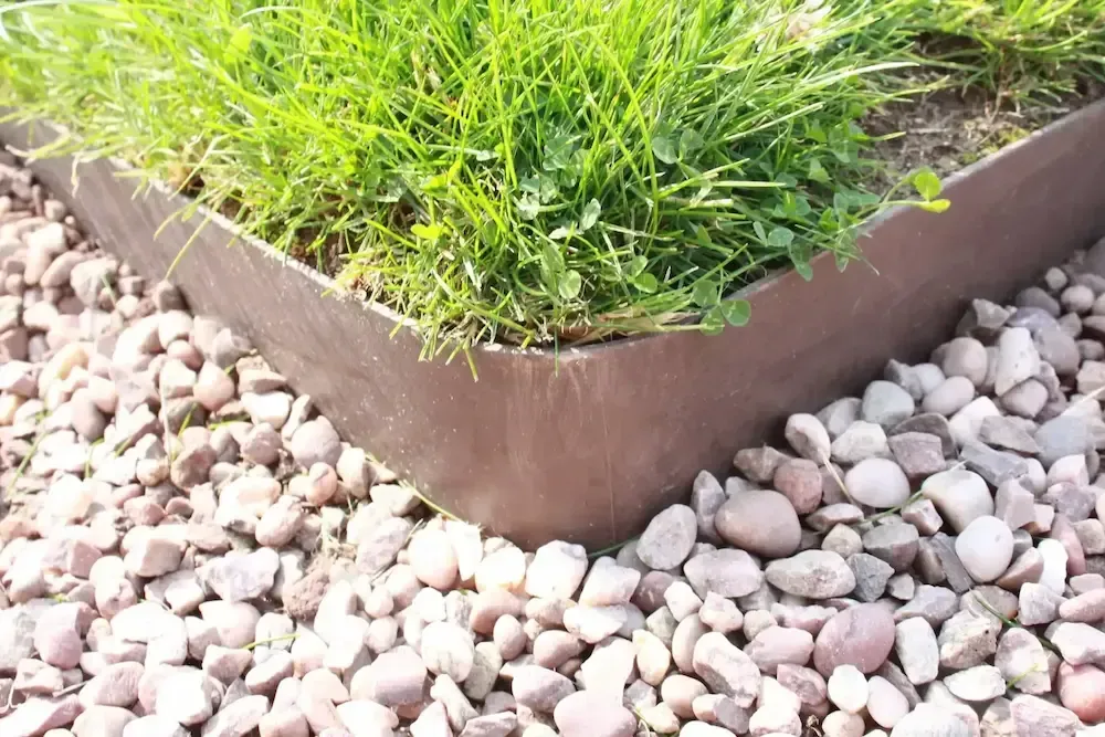 A lawn edging is surrounded by rocks and grass.