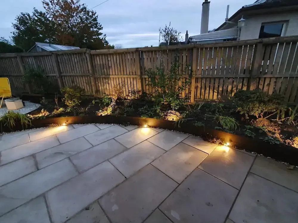 A patio with lights on it and a wooden fence in the background