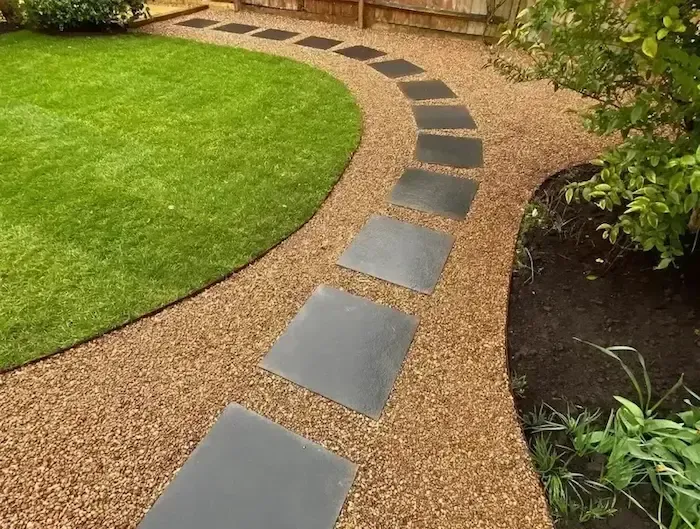 A walkway in a garden with stepping stones and gravel