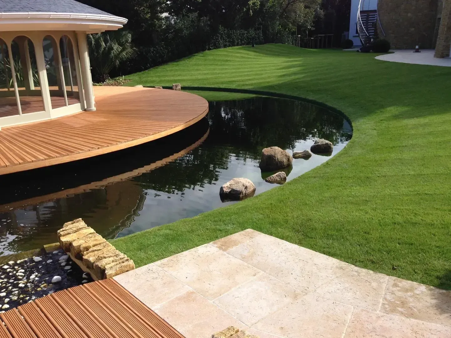 A house with a wooden deck and a pond in front of it