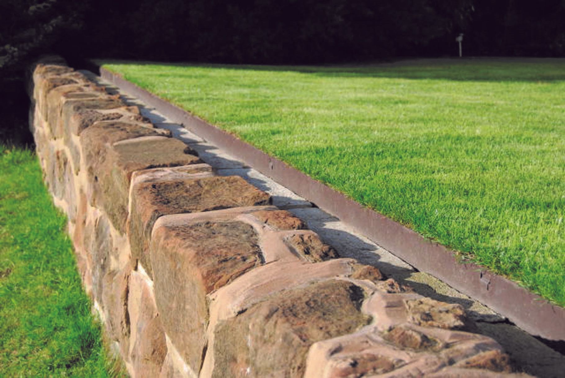 EverEdge Garden Edging on a lawn against a stone wall