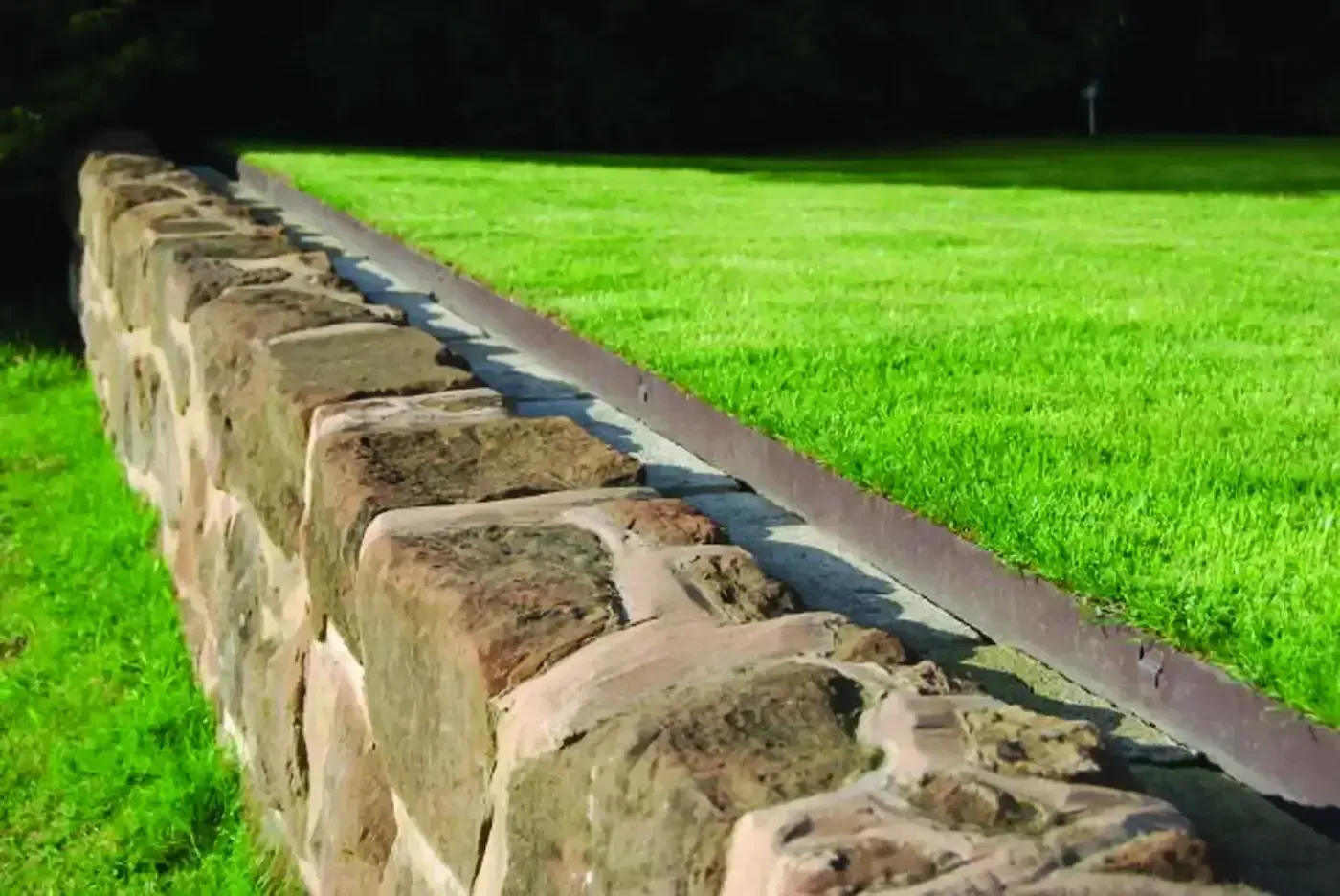 A lawn edging is surrounded by rocks and grass.