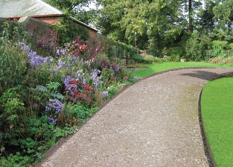 A gravel path in a garden with flowers on the side