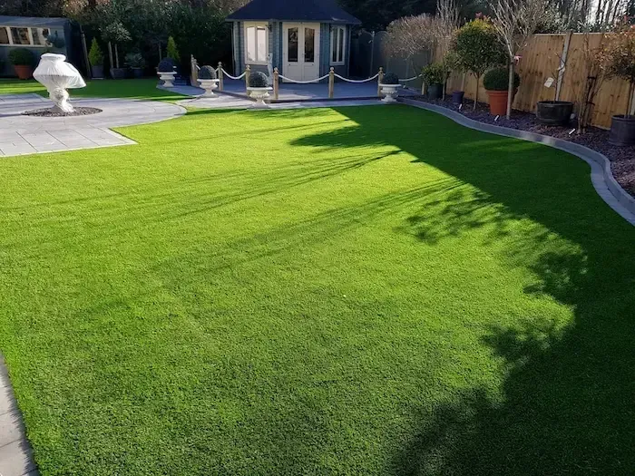 A lush green lawn in a backyard with a gazebo in the background.